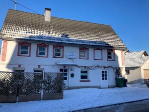 古默斯巴赫的住宿－Ferienhaus Lieberhäuschen，雪中带围栏的白色房子