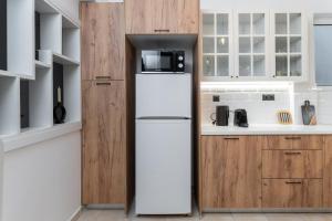 a white refrigerator in a kitchen with wooden cabinets at Blue Chill Paradise Seaview Suite w/ Kingbed in Piraeus