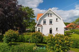 ein weißes Haus mit orangefarbenem Dach in der Unterkunft Villa Hygge Kappeln - Ferienwohnungen in Kappeln