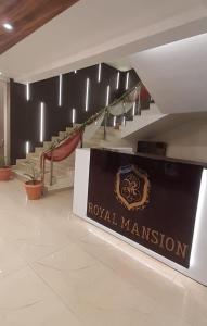 eine Lobby mit einem Schild und einer Treppe des königlichen Herrenhauses in der Unterkunft ROYAL MANSION in Muzaffarpur