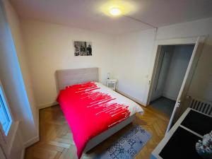 a small bedroom with a red blanket on a bed at A deux pas du lac Leman ( Ouchy) joli appartement in Lausanne