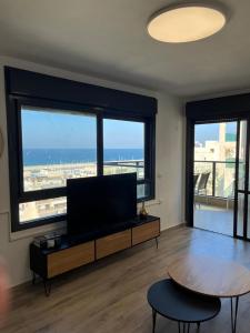 a living room with a flat screen tv and a table at Blue Sea Suite in Ashkelon