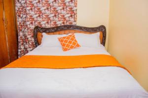 a bed with an orange blanket and a brick wall at Jenna stays in Nyeri