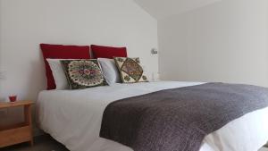 1 dormitorio con cama blanca y almohadas en SulSeixe Guesthouse, en Odeceixe