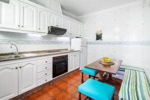 cocina con armarios blancos, mesa y sillas en Casa Guatifay en Puerto del Carmen