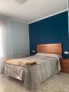sypialnia z dużym łóżkiem i niebieską ścianą w obiekcie Apartamentos M° Esther w mieście A Lanzada