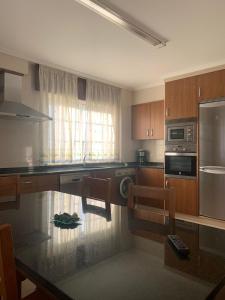 uma cozinha com armários de madeira e uma bancada em Apartamentos M° Esther em A Lanzada