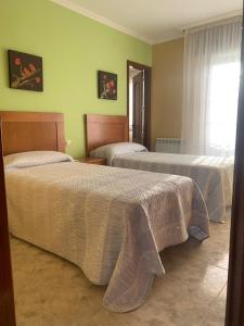 a hotel room with two beds and a window at Apartamentos M° Esther in A Lanzada