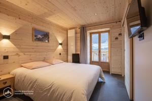 een slaapkamer met een groot bed in een houten kamer bij "Le Temps Suspendu" in Termignon