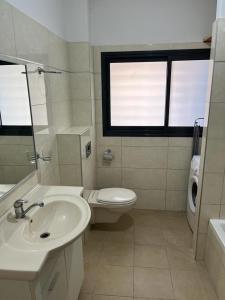 a bathroom with a sink and a toilet and a window at Blue Sea Suite in Ashkelon