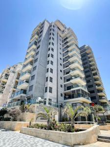 un edificio de apartamentos alto con palmeras delante en Blue Sea Suite, en Ashkelon