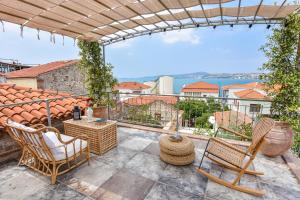 een patio met stoelen en uitzicht op het water bij Lunaria Guest House in Ayvalık