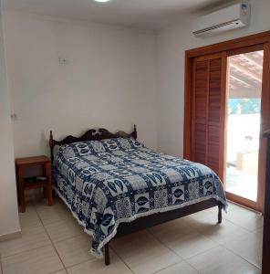 a bedroom with a bed with a blue and white blanket at Recanto Do Sossego Suítes Hospedagem Domiciliar na Praia in Boicucanga