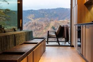 a room with a couch and a chair and a large window at Stejeris Nature-Inspired Luxury Apartment in Braşov