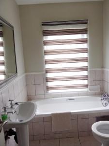 baño con bañera, lavabo y ventana en luxury with power backup, en Johannesburgo