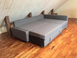 um sofá cinzento num quarto com piso de madeira em Korsanäs em Listerby