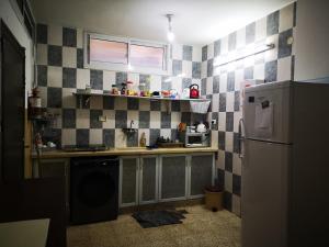 a kitchen with black and white tiled walls and a refrigerator at YCC Guesthouse in Nablus