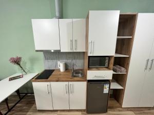 cocina con armarios blancos, fregadero y microondas en SN Apartments en Osh