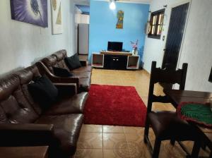 a living room with a leather couch and a red rug at Mar&cia chácara temporada in São Sebastião