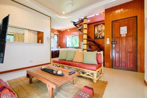 a living room with a red couch and a wooden staircase at Villa Siam Lanna at Kantiang Bay in Ko Lanta
