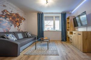 ein Wohnzimmer mit einem Sofa und einem TV in der Unterkunft Apartament Habel, MyWeek in Bystrzyca Kłodzka