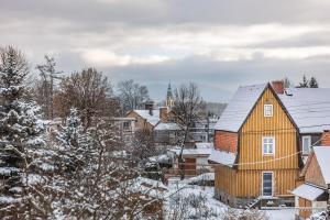 a yellow house in a snow covered town at Apartament Habel, MyWeek in Bystrzyca Kłodzka