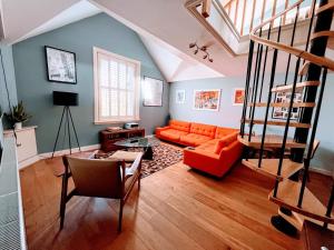 a living room with an orange couch and a staircase at Retro penthouse flat, close to parks and centre in Liverpool