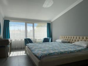 a bedroom with a bed and a desk and windows at RZA HOTEL in Aşağı İmrahor