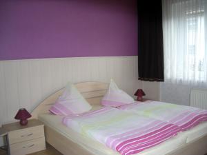 Bett mit rosa und weißer Bettwäsche und Kissen in der Unterkunft Ferienwohnung Böhnstedt in Thale