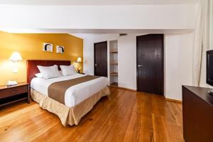 um quarto de hotel com uma cama e uma televisão de ecrã plano em Suites Teca Once em Cidade do México
