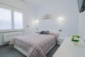 una camera bianca con un letto con una coperta a quadri di H11 Bilocale Arma-Taggia - 1A a Taggia
