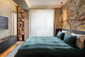 a bedroom with a large green bed with a stone wall at Stejeris Nature-Inspired Luxury Apartment in Braşov
