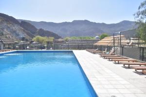 una gran piscina con sillas y montañas en el fondo en Raices Departamento 2 en San Rafael