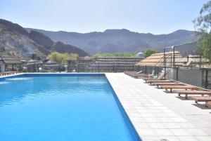 Una gran piscina con sillas y montañas al fondo. en Raices Departamento 2, en San Rafael