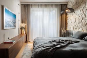 a bedroom with a bed and a stone wall at Stejeris Nature-Inspired Luxury Apartment in Braşov