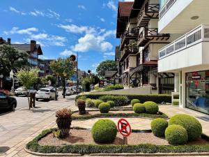 una calle con arbustos y un cartel de no estacionamiento frente a un edificio en Morada da Montanha Centro by Achei Gramado, en Gramado