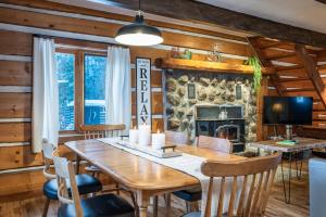a dining room with a table and a fireplace at Chalet du Sous-Bois By My Tremblant Location in Saint-Faustin