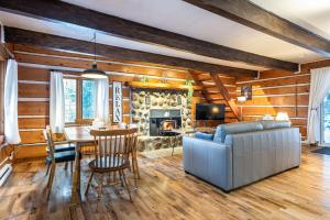 a living room with a couch and a table and a fireplace at Chalet du Sous-Bois By My Tremblant Location in Saint-Faustin
