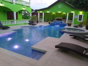 a swimming pool in front of a green building at PESHERES INN & SPA in Bon Accord