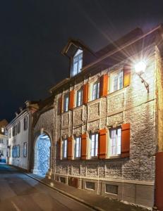 a brick building with orange shuttered windows at night at Gasthof zum Schwan in Sommerach