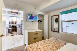 a bedroom with a bed and a kitchen with a tv at Oceana 203 West in St. Pete Beach