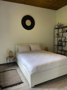 a white bed in a bedroom with a clock on the wall at Baia Seixal Oceanfront in Seixal