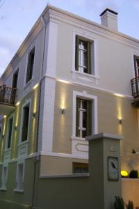 a white building with a clock in front of it at Room in Faneromeni's grove in Kastoria