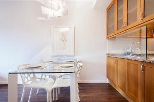 uma cozinha com uma mesa de vidro e cadeiras brancas em Suites4days Provenza Apartment em Barcelona