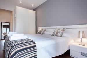 um quarto branco com uma grande cama branca com almofadas em Suites4days Provenza Apartment em Barcelona