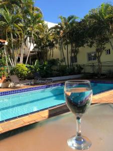 a glass of wine sitting on a table next to a swimming pool at POUSADA EVELINA in Foz do Iguaçu