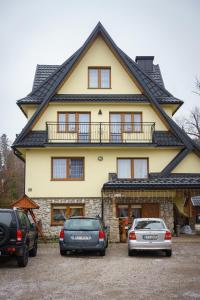twee auto's geparkeerd voor een huis bij Leśna Ostoya in Białka Tatrzanska