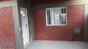 eine rote Backsteinmauer mit einem Fenster und einer Tür in der Unterkunft Departamento La Mariposa in Perito Moreno + 1 Foto