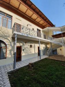 a white house with a balcony and a yard at Chorsu Inn in Tashkent