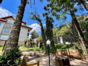 un parque con bancos, un edificio y árboles en Apartamento Garten Haus 2 suítes by Achei Gramado, en Gramado